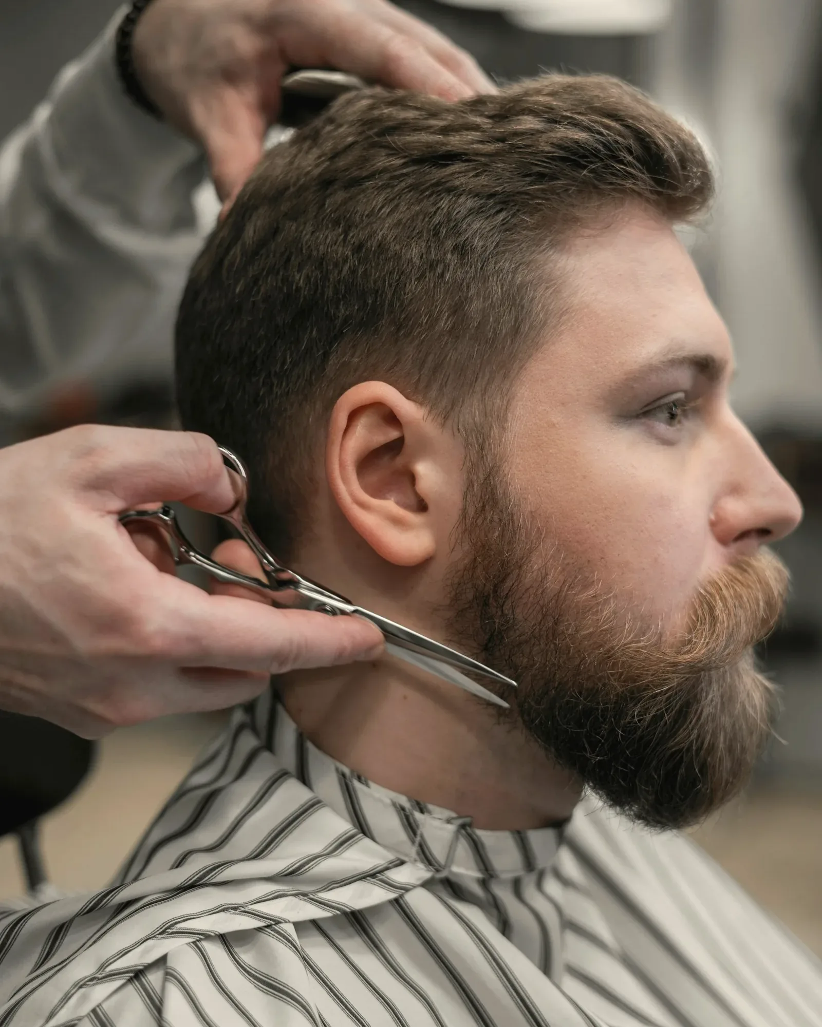Un barbier taille la barbe d’un homme aux ciseaux