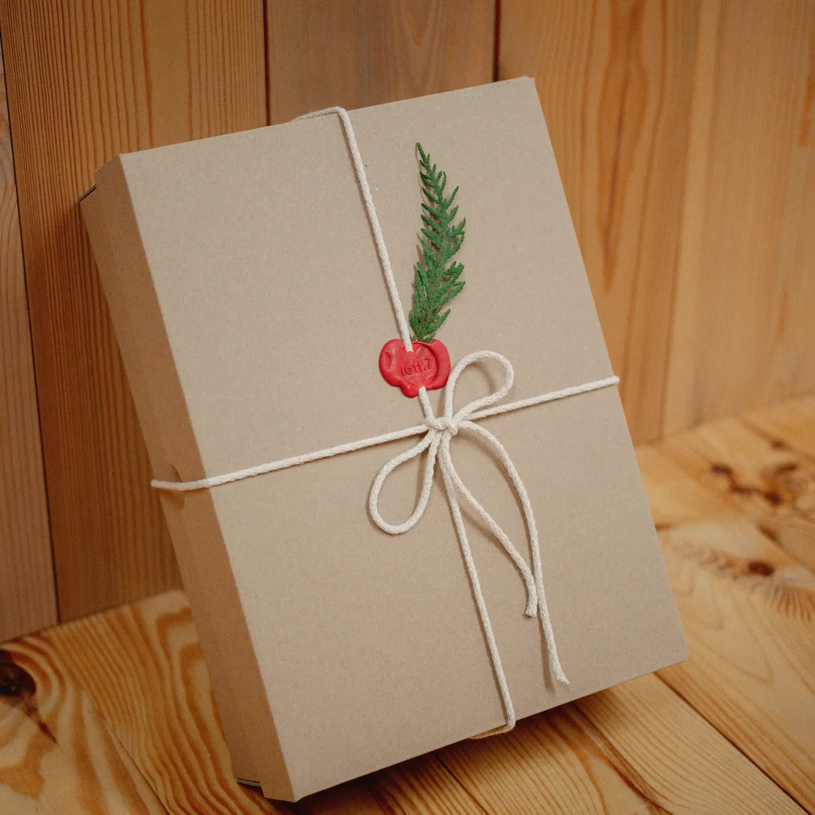 Un paquet cadeau en papier kraft, noué d’une ficelle et d’une branche de sapin