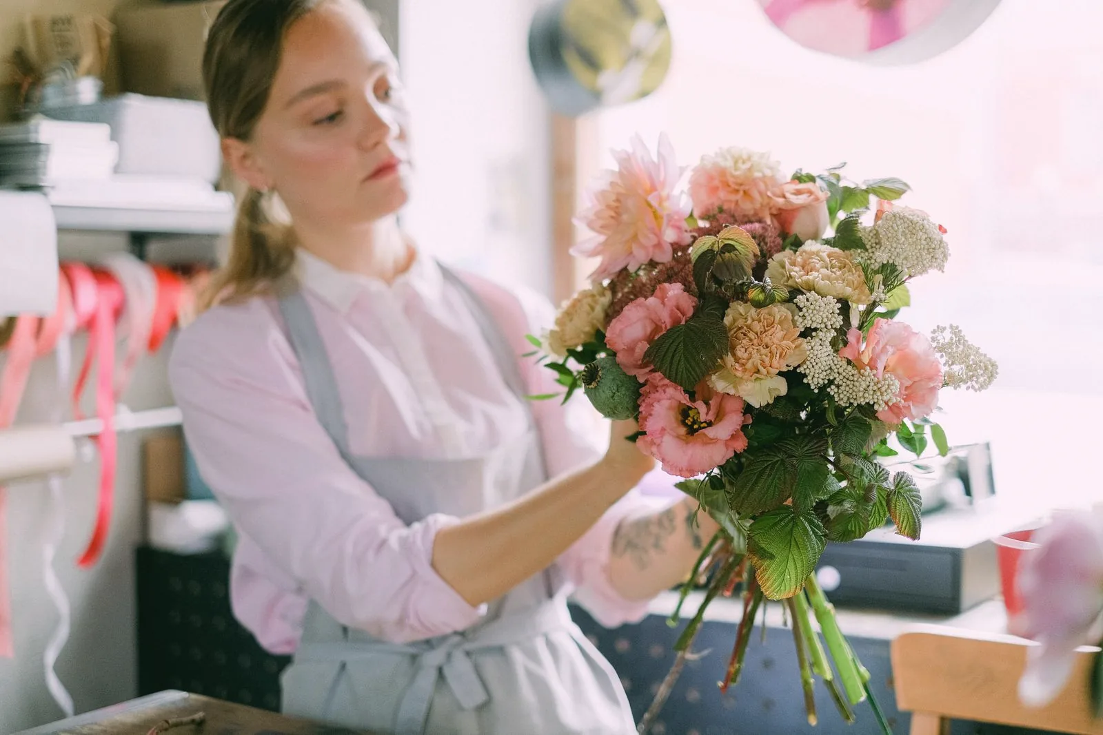 Une fleuriste compose un bouquet aux tons pêche